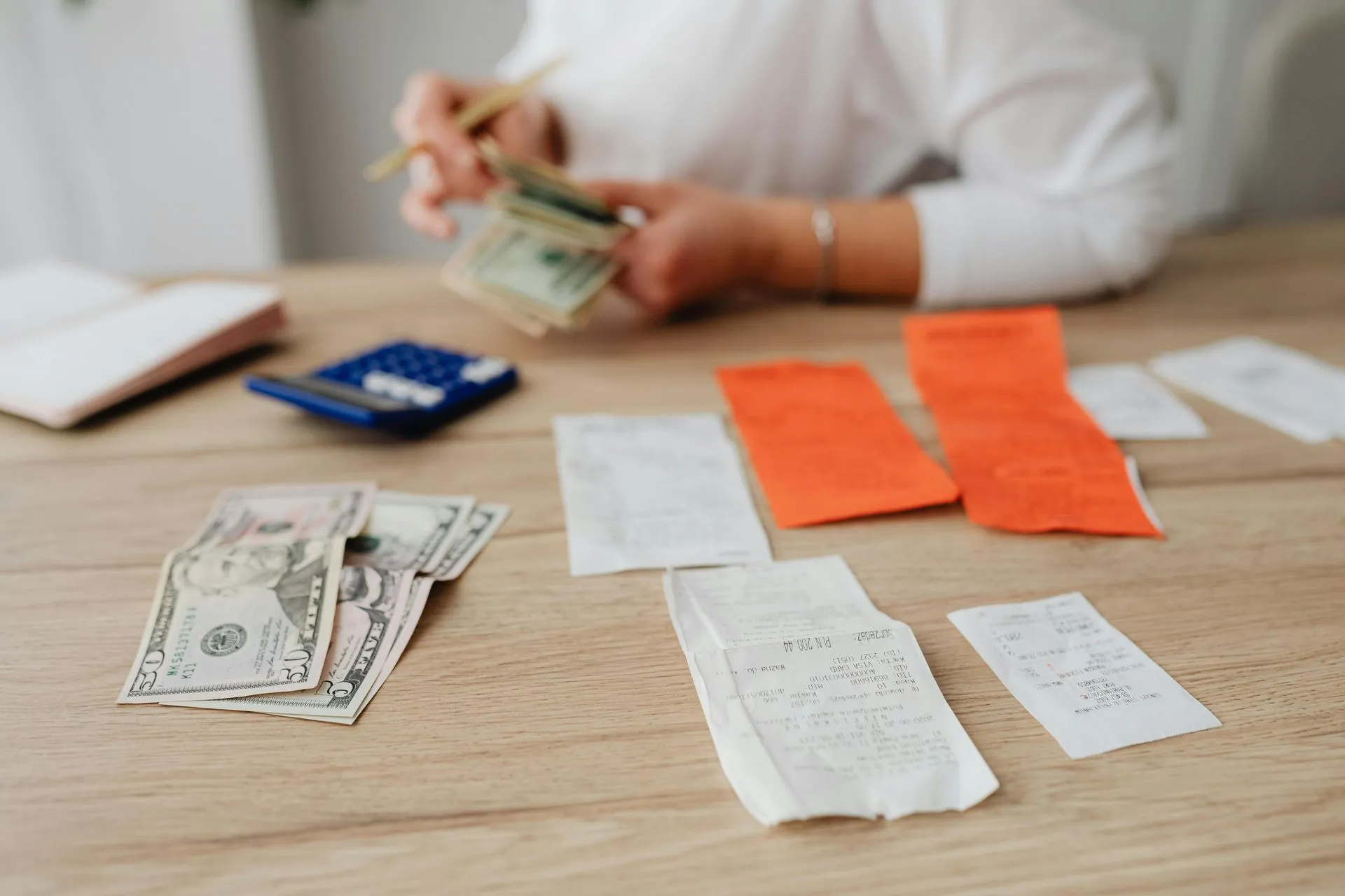 Business receipts and cash being counted with a calculator for expense tracking.