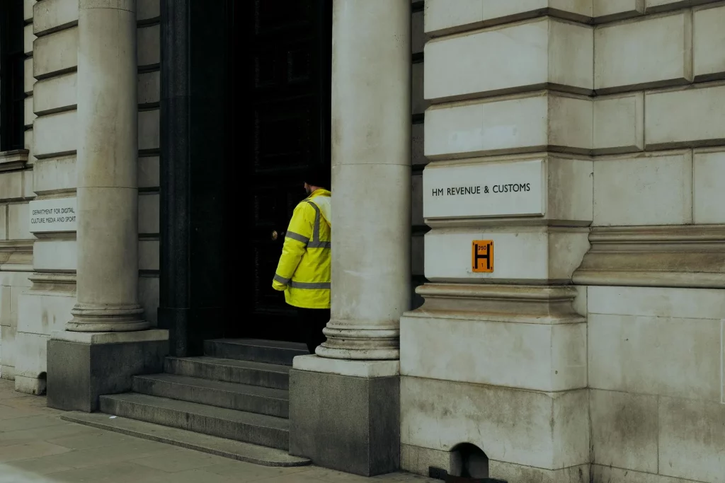 Entrance to HM Revenue and Customs UK government building with a security guard.