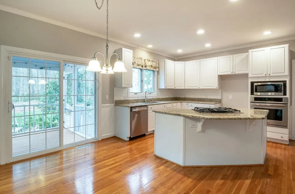 Modern kitchen with island, white cabinets, and hardwood flooring.
