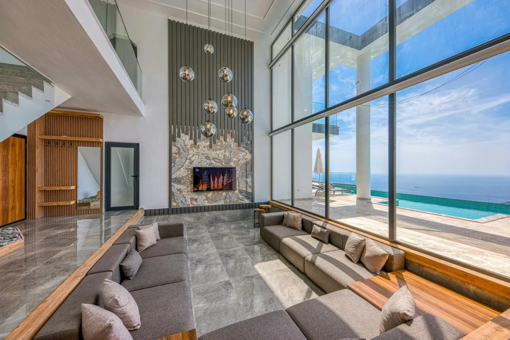 Luxury living room with modern furniture, panoramic windows, and ocean view.
